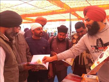 Sukhmandeep Singh, Atam Pargas volunteer, explaining Atam Pargas Publications to visitors.